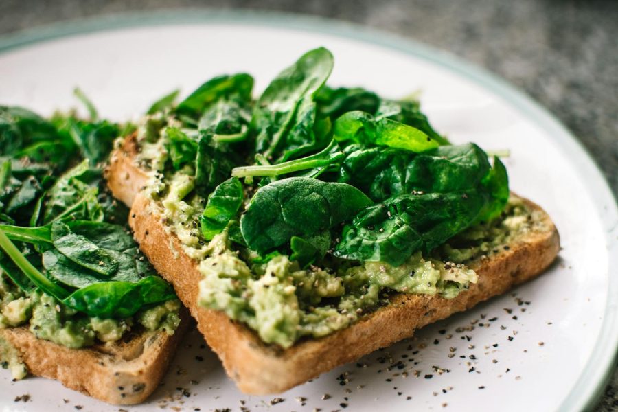 Close-up of a homemade avocado and spinach sandwich on whole grain toast.