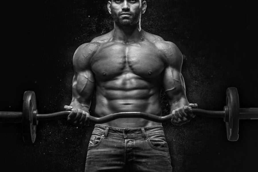 Black and white portrait of a muscular man lifting weights, showcasing strength and fitness.