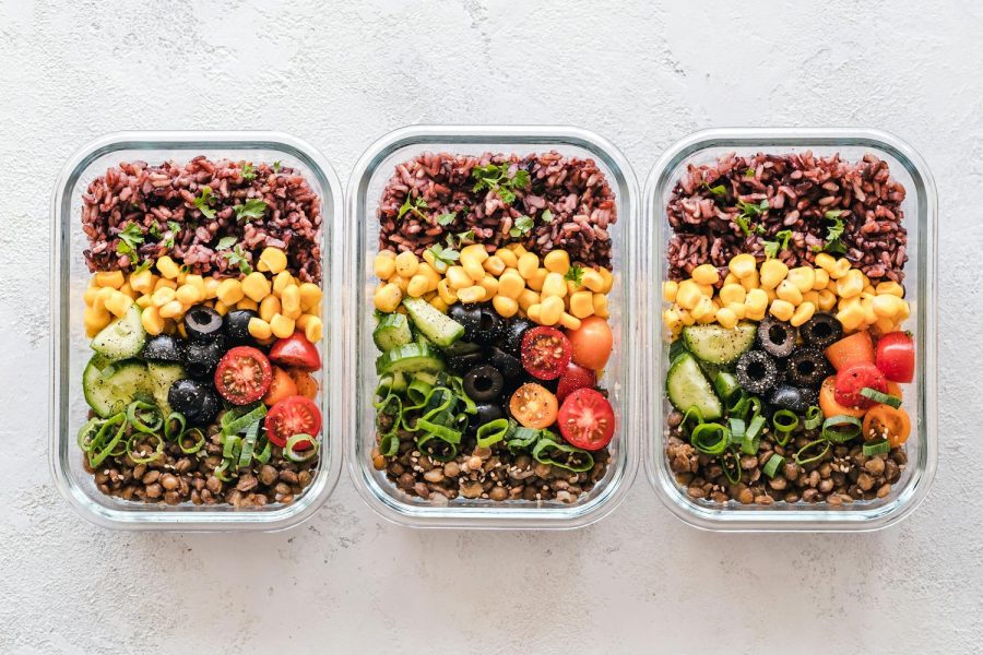 Colorful healthy meal prep with corn, olives, tomatoes, and lentils in glass containers. Perfect for mindful eating.