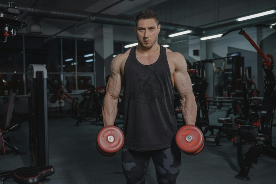 Man in gym lifting dumbbells, showcasing strength and fitness.