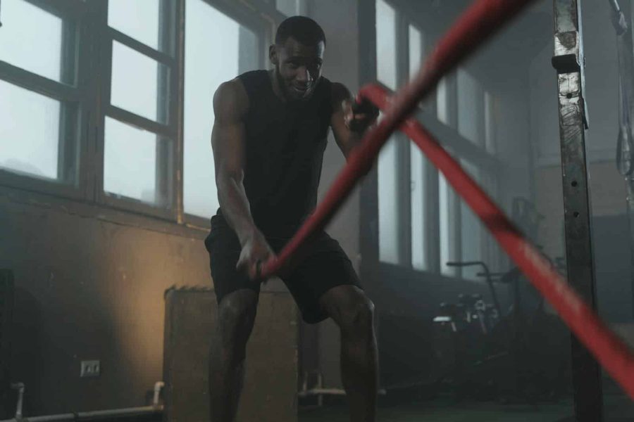 Fit man working out with battle ropes in a gym, showcasing strength and determination.