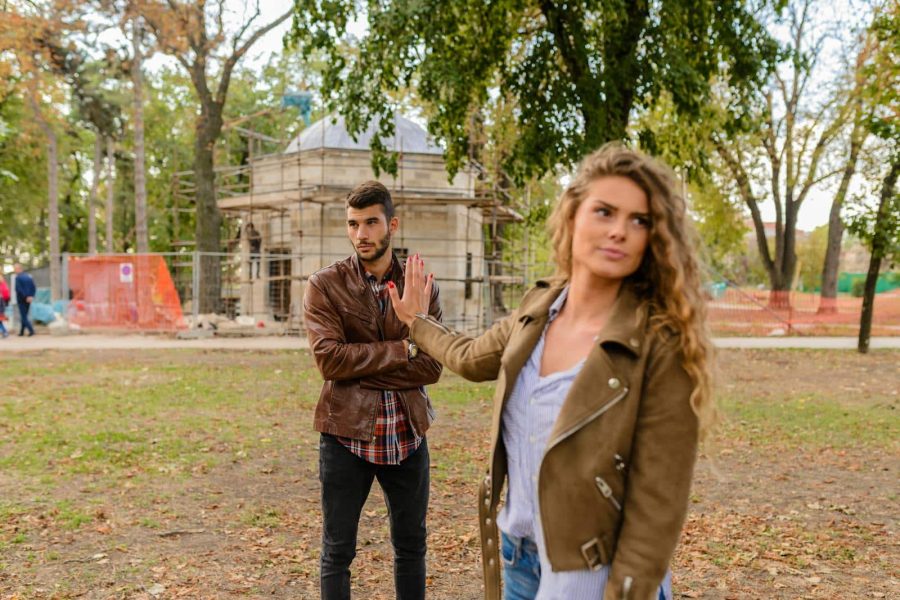 A couple faces disagreement outdoors in a park setting showcasing emotional expressions.